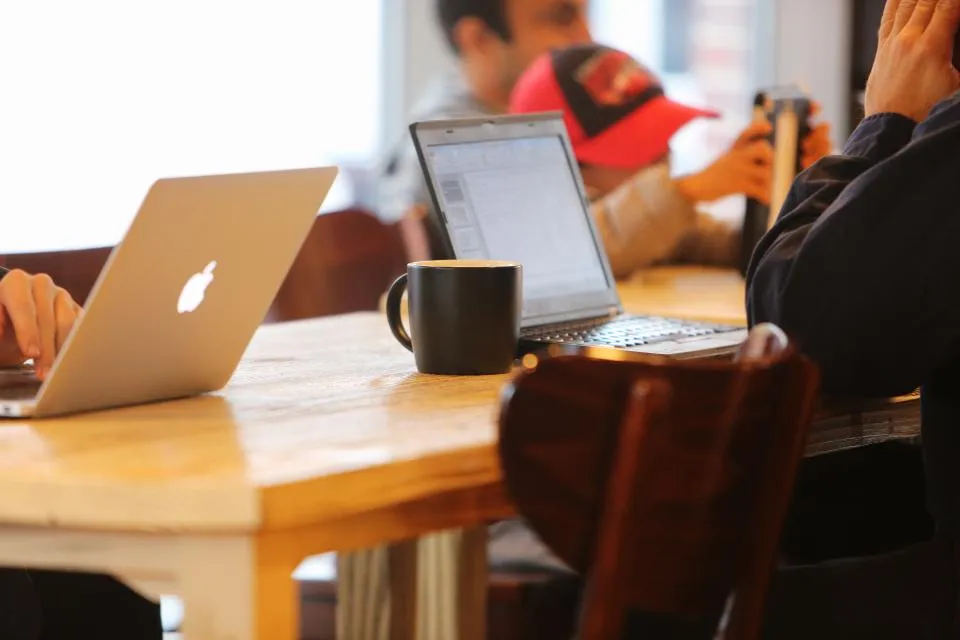 Dua laptop dan secangkir kopi di atas meja kayu